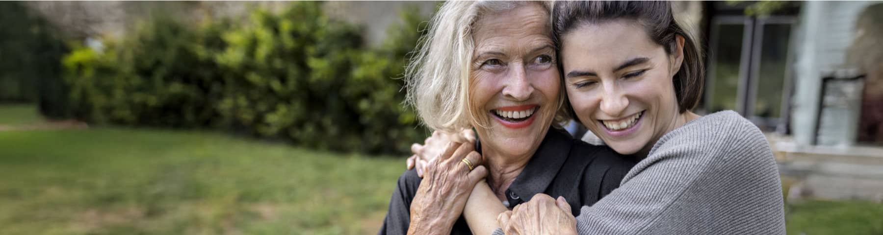 Older adult smiling while being embraced by a loved one at home