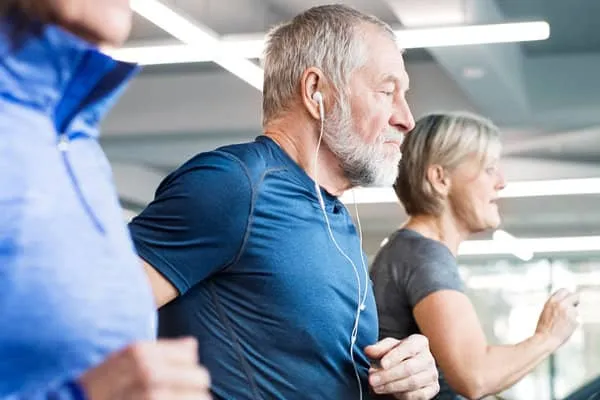 A group of older adults exercising on treadmills next to one another, as part of their cardiac rehab program.